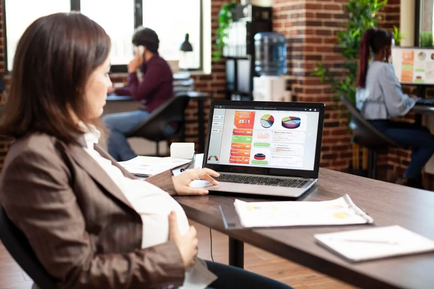 A pregnant woman using a laptop at a desk