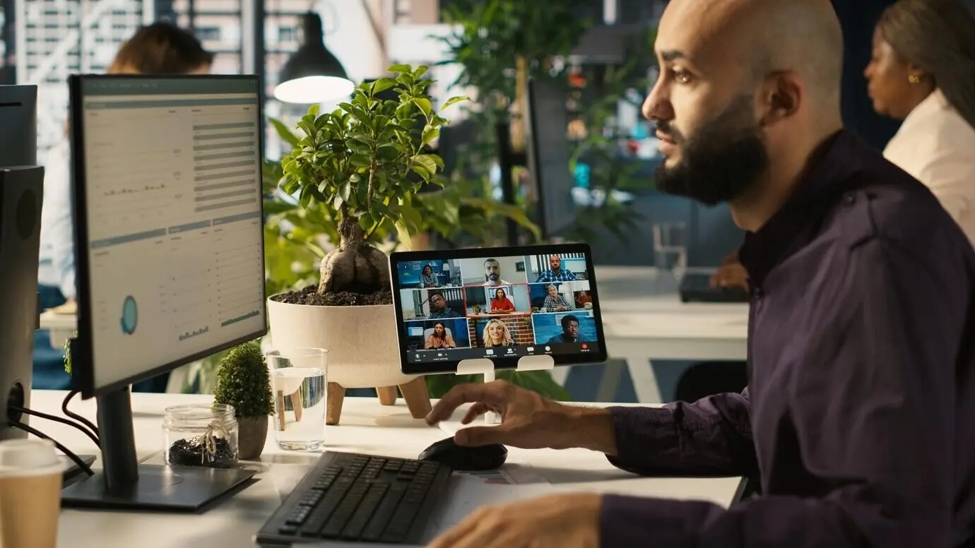 An office worker speaking with colleagues via an internet video call.